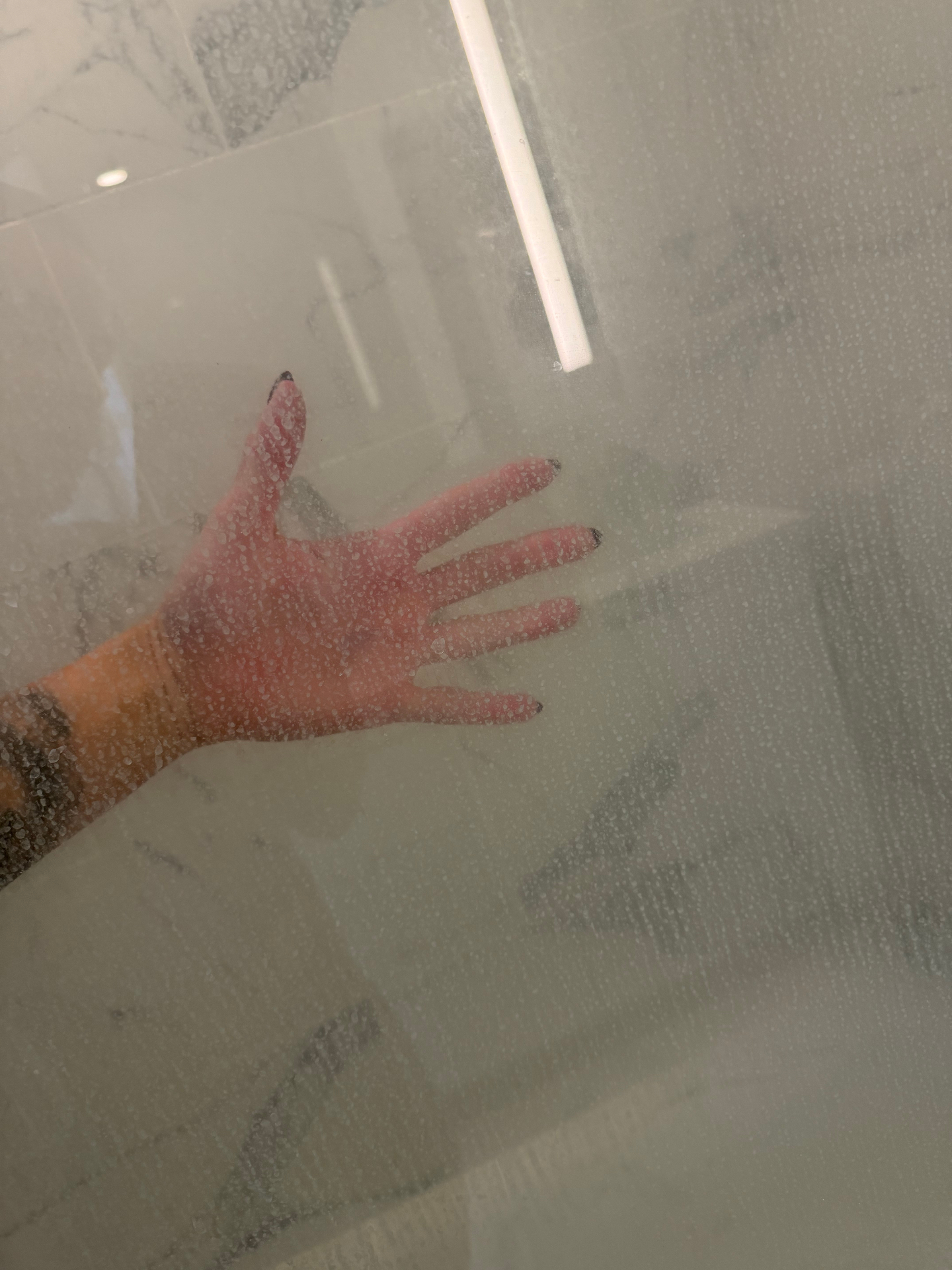 Water-spotted shower glass door before a deep bathroom cleaning